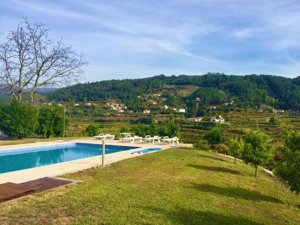 einem Pool mit Stühlen und einem Hügel im Hintergrund in der Unterkunft Quinta do Pêso in Amarante