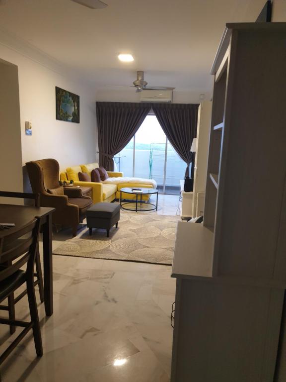a living room with a yellow couch and a table at 5-Bedroom Family Apartment in Seri Kembangan