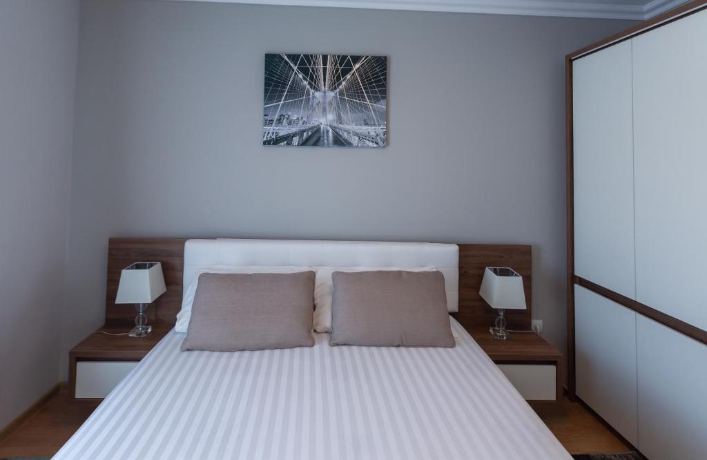 een slaapkamer met een wit bed met 2 kussens bij Apartament Saguna in Sînnicolau Mare
