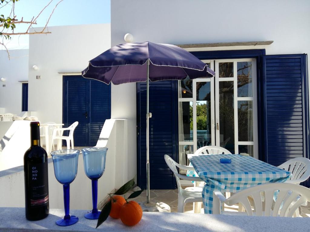 a table with a purple umbrella and two wine glasses at Bungalows Ingrid in Tolo