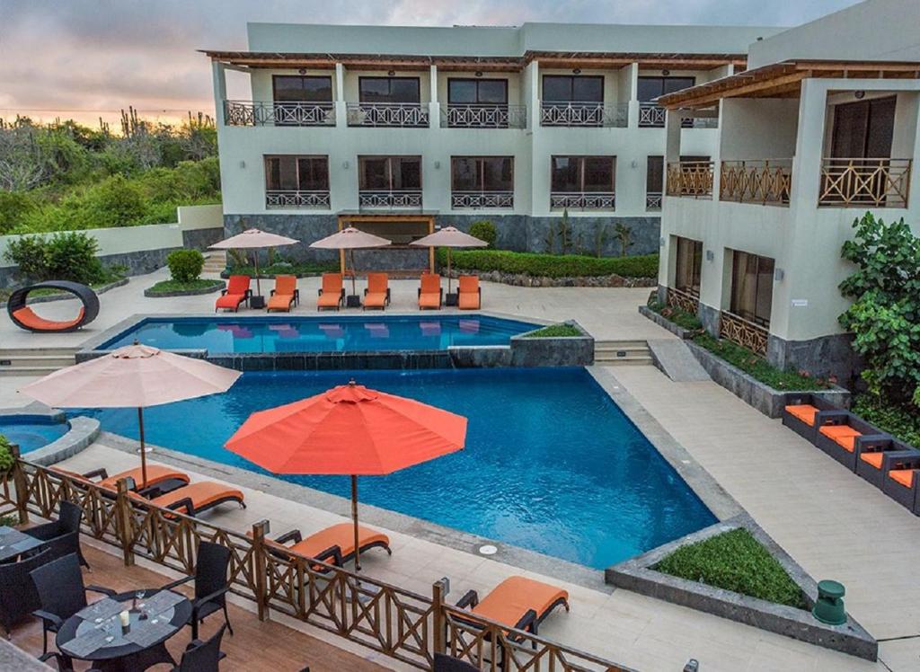 a swimming pool with umbrellas and chairs and a hotel at Palo Santo Galápagos Hotel in Puerto Ayora