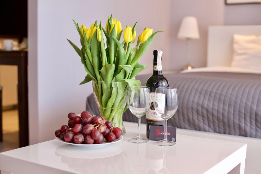 una mesa con una botella de vino y un bol de fruta en Kraków Apartments - Friedleina Studio Apartments, en Cracovia