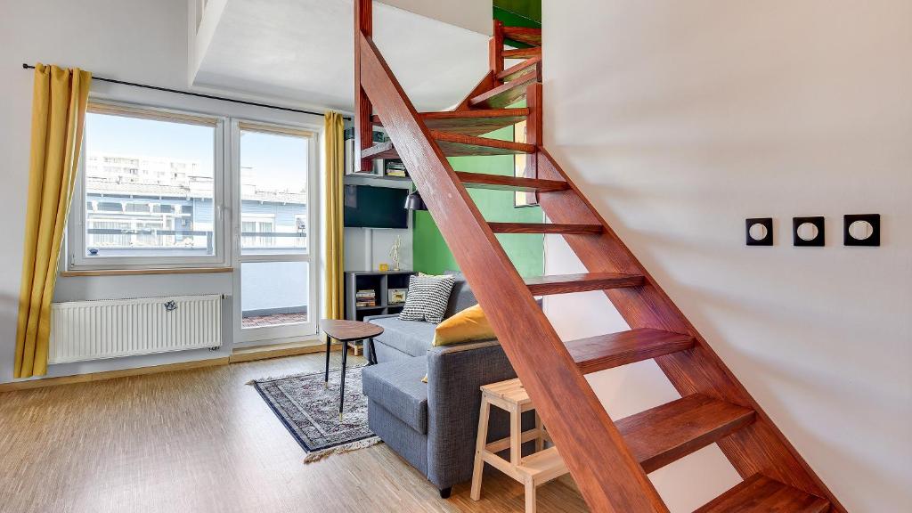 eine Treppe in einem Wohnzimmer mit einem blauen Sofa in der Unterkunft Dom & House - Apartment Smart Studio Sopot in Sopot