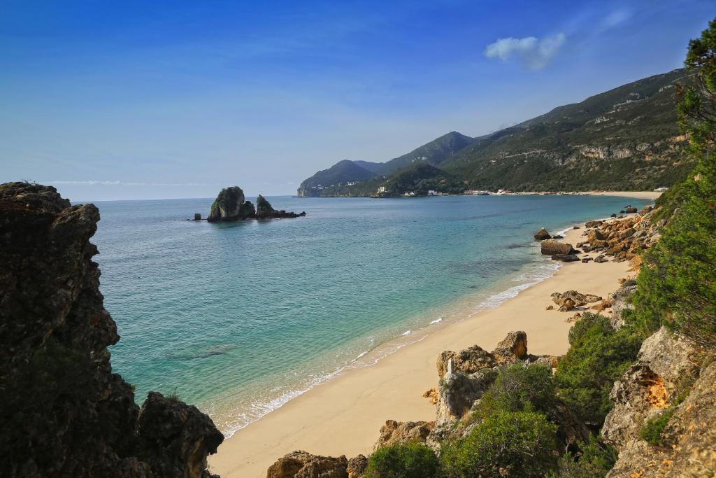 a beach with a rock formation in the water at RM The Experience - Small Portuguese Hotels in Setúbal