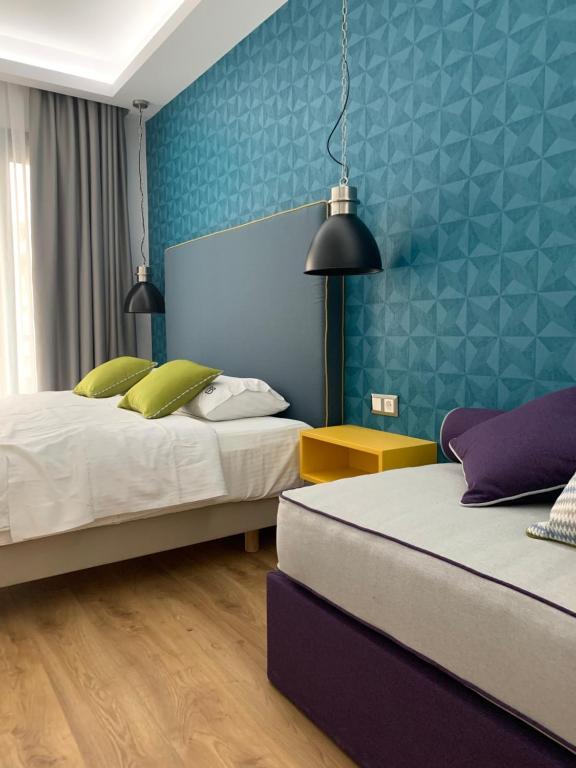 a bedroom with two beds and a blue wall at White Bottle Superior Apartments in Thessaloniki