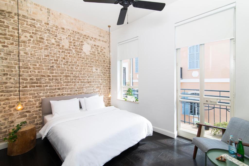 a bedroom with a white bed and a brick wall at Oliver in Tel Aviv