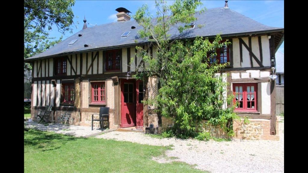 una casa vieja con una puerta roja y un árbol en Le Hibou Perché, en Lieurey