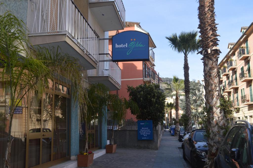 a sign on a building on a street with palm trees at Hotel Gilda in Laigueglia