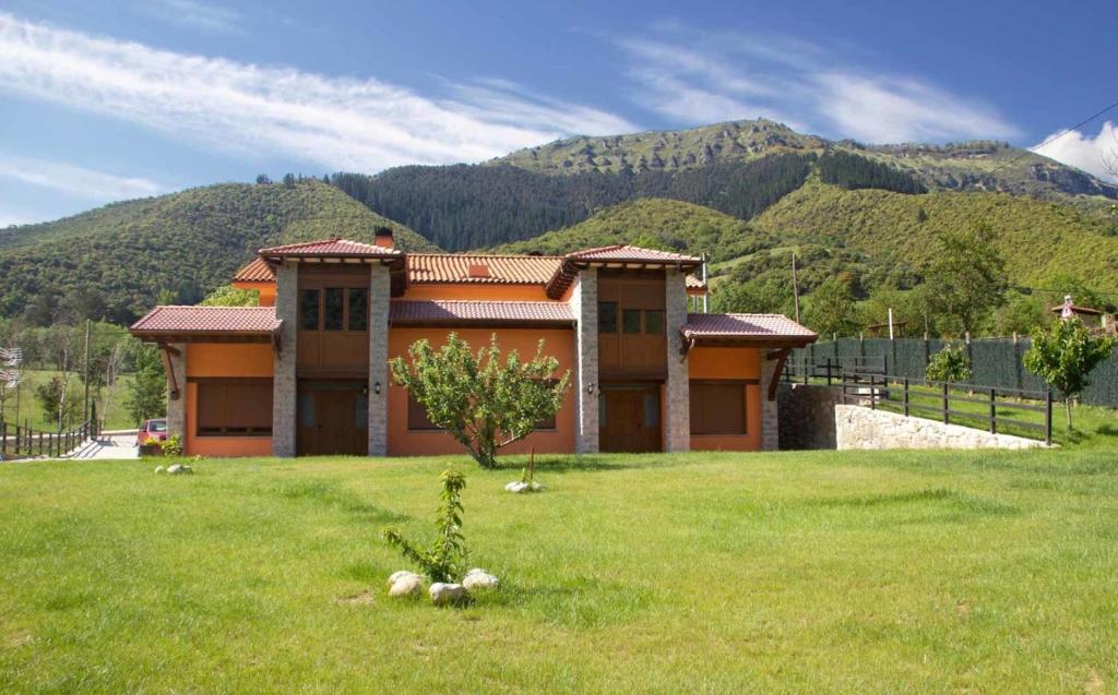 a house in the middle of a field with a mountain at APARTAMENTOS CAMINO SANTO TORIBIO in Mieses