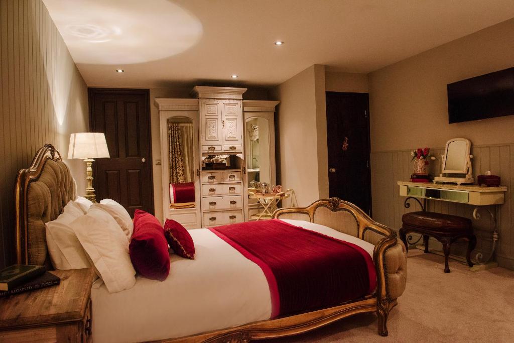 a bedroom with a large bed with red and white pillows at The Joiners Arms in Chathill