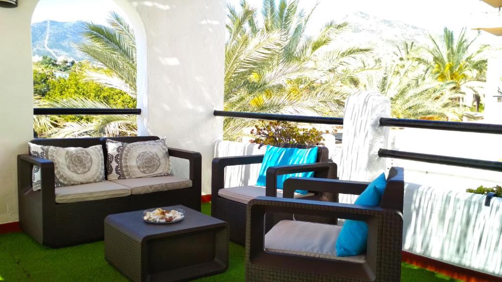 d'un balcon avec des chaises, une table et des palmiers. dans l'établissement Pueblo Blanco, à Benalmádena