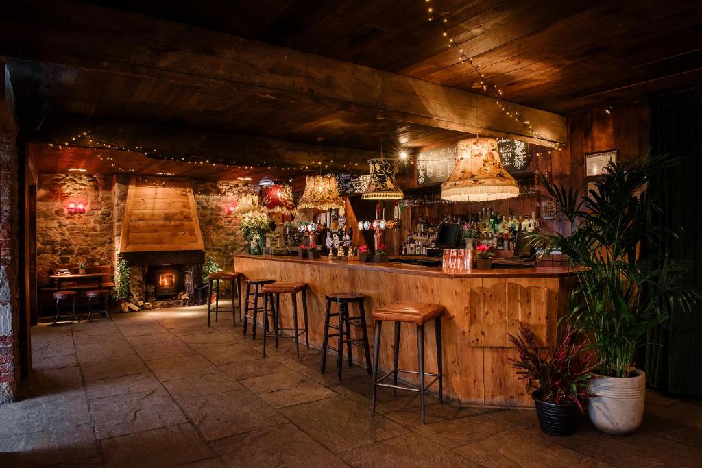 a bar with stools in a room with a fireplace at The Joiners Arms in Chathill