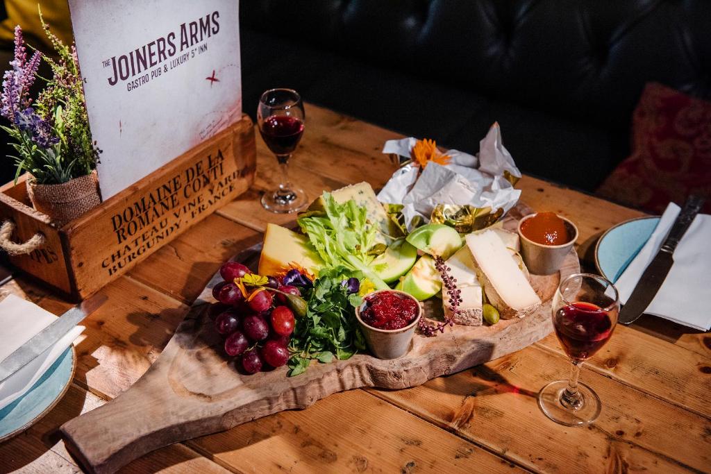a wooden table with a plate of food and two glasses of wine at The Joiners Arms in Chathill