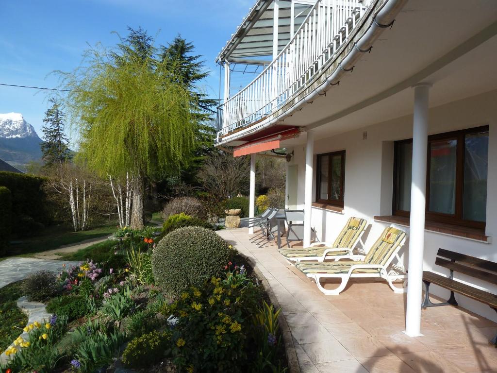 eine Veranda eines Hauses mit Stühlen und Blumen in der Unterkunft Vue sur les montagnes in Embrun