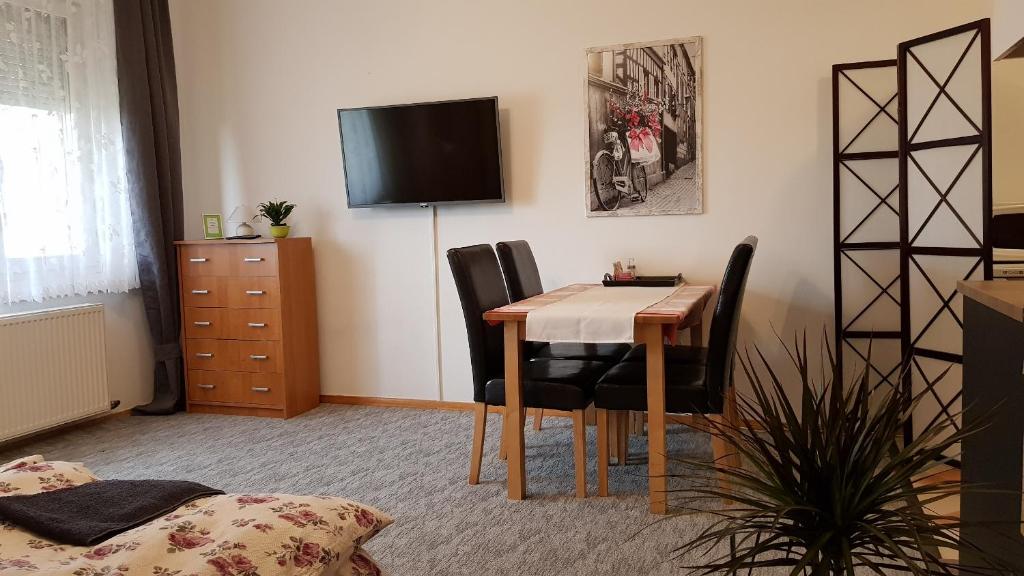 Habitación con mesa, sillas y TV. en ÁRPÁD Apartman, en Szekszárd