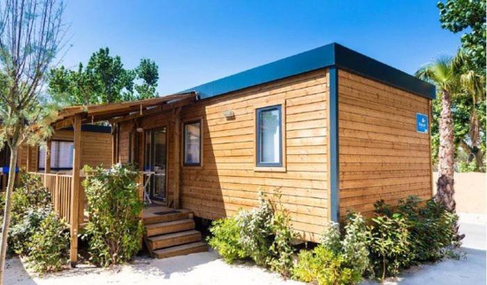 una pequeña casa de madera con porche y escaleras en Camping Paris-Est, en Champigny-sur-Marne