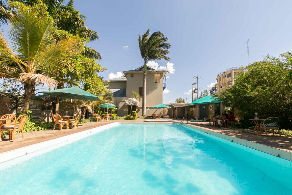 a large swimming pool with chairs and umbrellas at Fahari Gardens Hotel in Nairobi