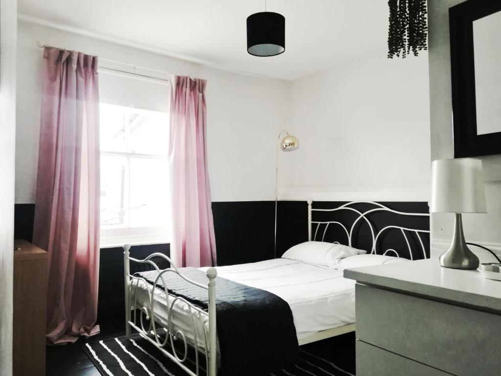 ウェリントンにあるThe Blue Mantleのベッドルーム1室(ピンクのカーテンと窓付きのベッド1台付)
