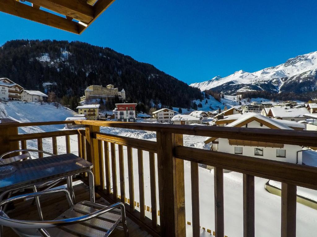 een balkon met een stoel en met sneeuw bedekte bergen bij Collina Hotel Garni in Nauders