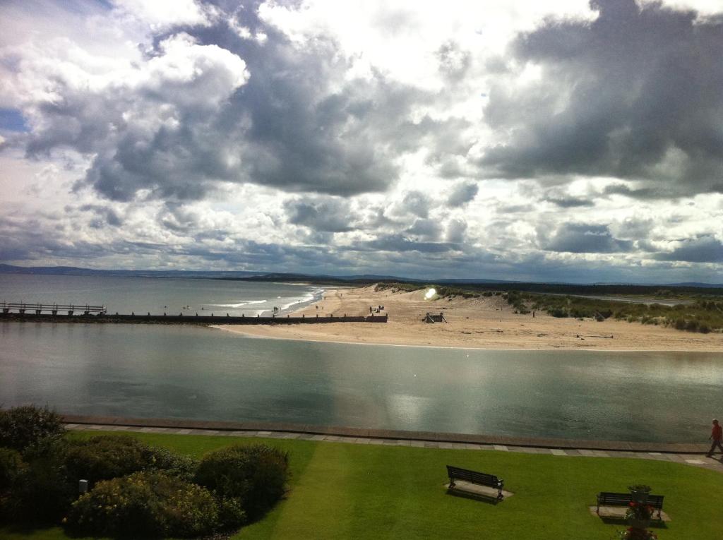 Blick auf einen Strand mit einem Pier und einer Bank in der Unterkunft The Jewel of the Moray Firth in Lossiemouth