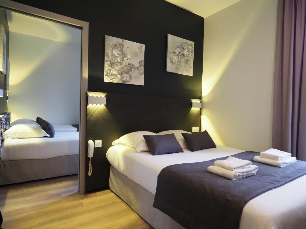 Cette chambre comprend 2 lits et un miroir. dans l'établissement Hôtel Le Biarritz - Vichy, à Vichy