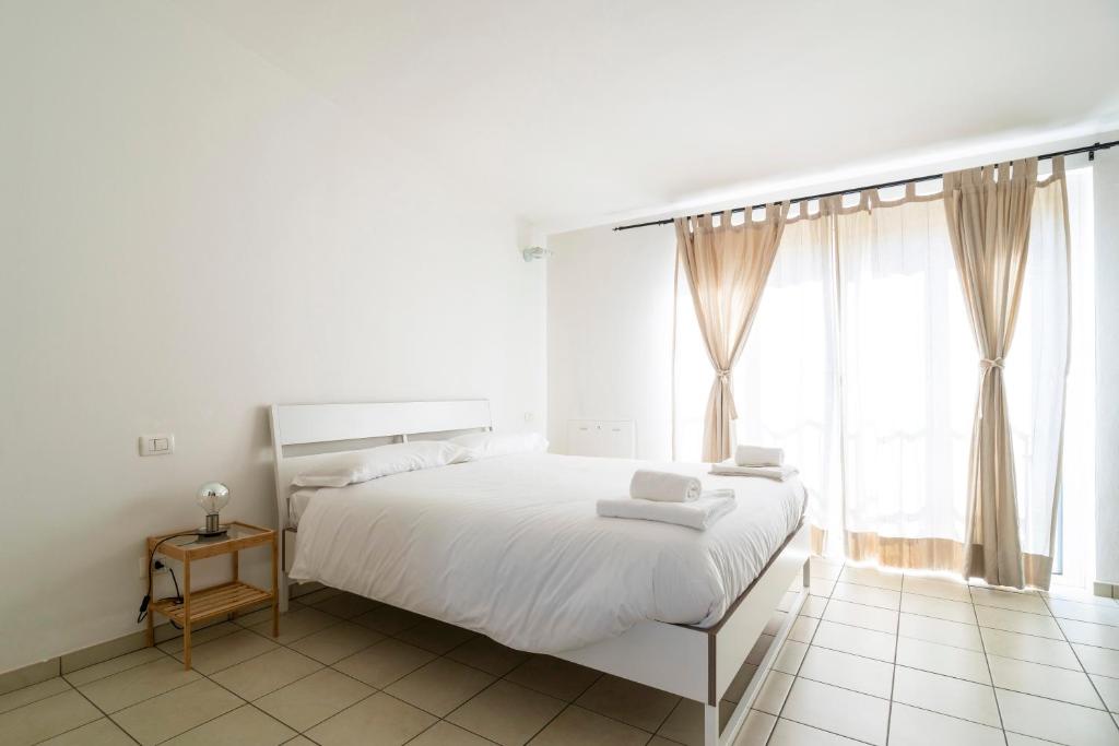 ein weißes Schlafzimmer mit einem weißen Bett und einem Fenster in der Unterkunft PrimoPiano - Garofalo A in Mailand