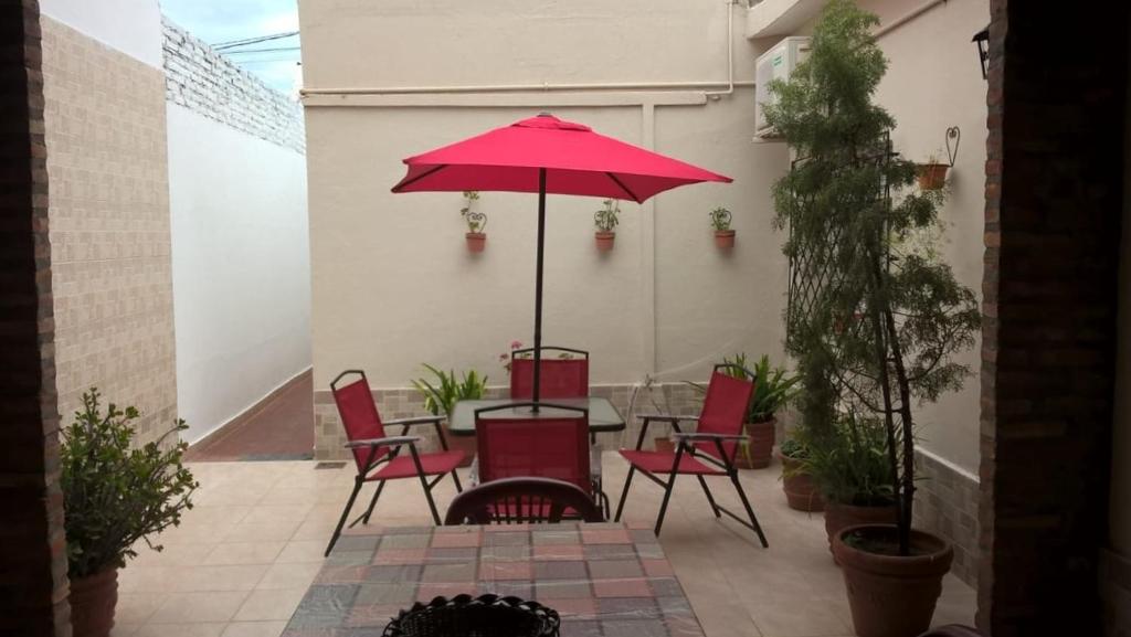 eine Terrasse mit einem Tisch und Stühlen mit einem roten Regenschirm in der Unterkunft Departamento Termas de Río Hondo in Termas de Río Hondo