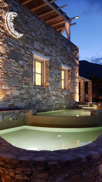 a stone house with a pool in front of it at Vrahos Boutique Hotel in Karavostasi