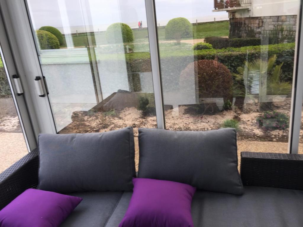 un divano con cuscini viola, seduto di fronte a una finestra di Maison contemporaine vue mer a Damgan