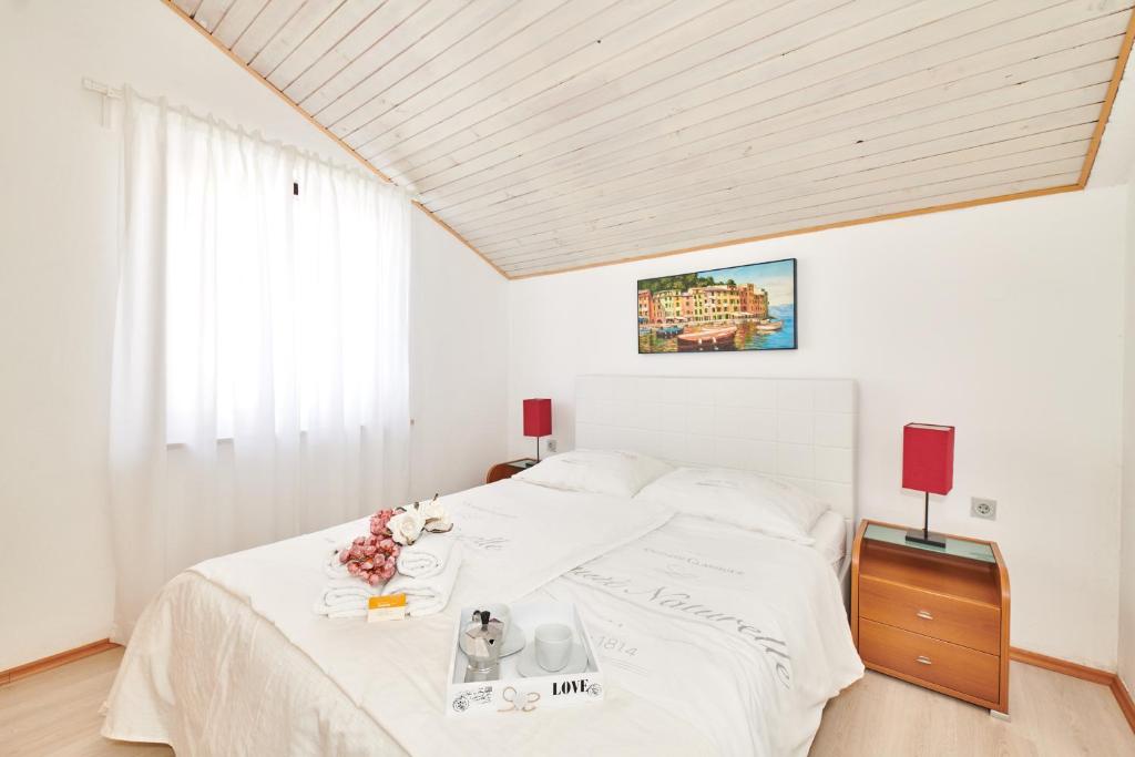 sypialnia z białym łóżkiem z kwiatami w obiekcie Apartments Gvarda w mieście Umag