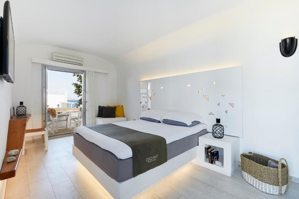 a bedroom with a large bed and a balcony at Vrahos Boutique Hotel in Karavostasi