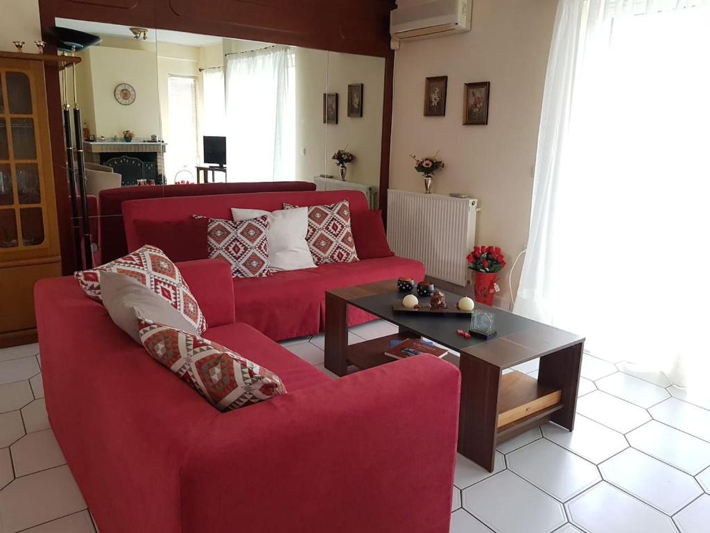 a living room with a red couch and a table at ANNA'S SWEET HOME in Nea Makri