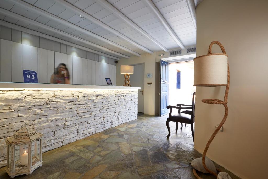 a woman sitting at a reception desk in a lobby at Vrahos Boutique Hotel in Karavostasi