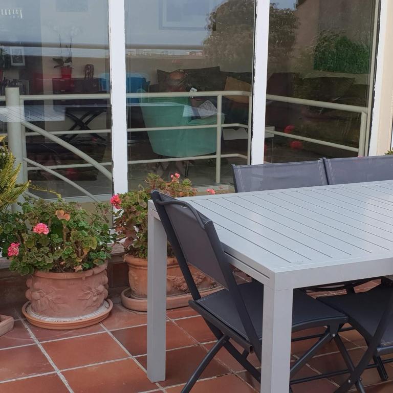 une table et des chaises blanches sur une terrasse couverte ornée de plantes dans l'établissement dupleix U Forcone, à Ajaccio