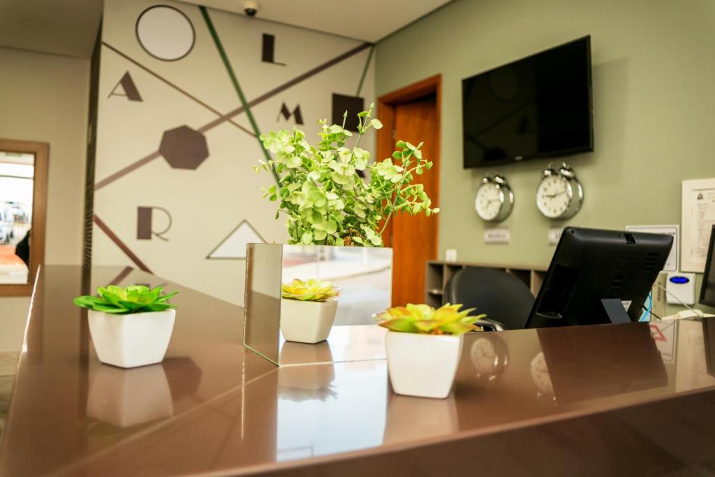 an office with three potted plants on a desk at Almaru Flat Ltda in Marília