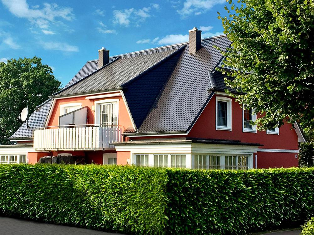 ein großes rotes Haus mit schwarzem Dach in der Unterkunft Ferienwohnung SÜN in Zingst