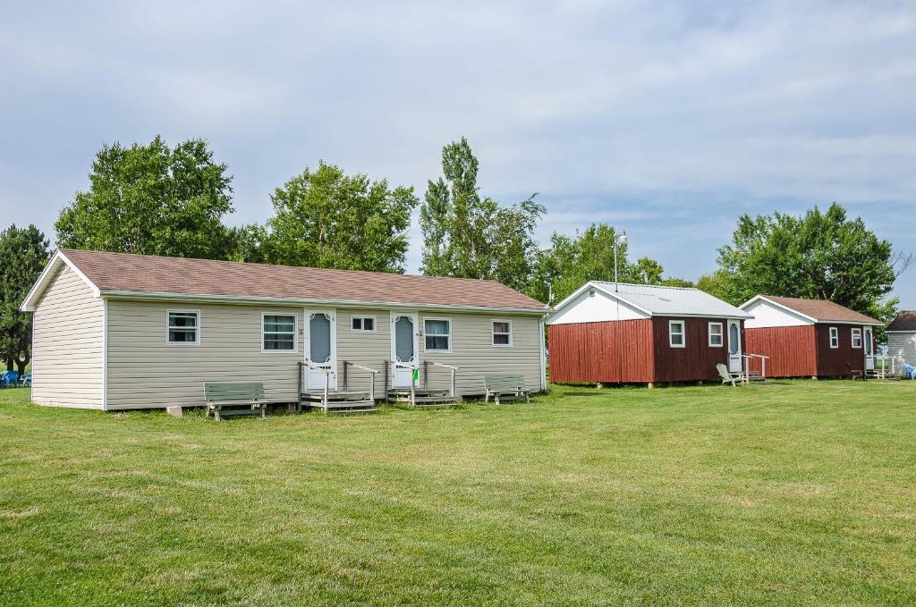 a white house with chairs in a grass field at Rachel's Motel and Cottages in Surrey