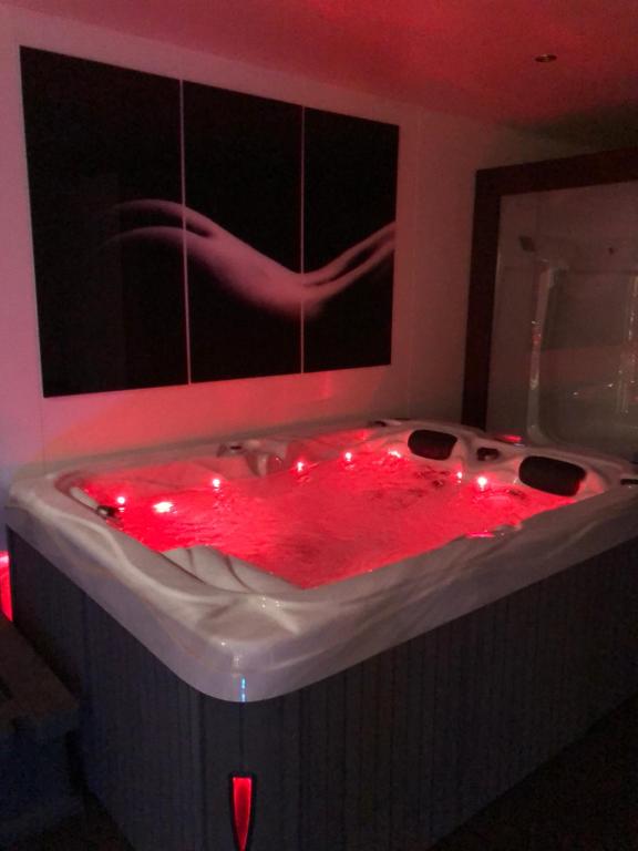 a red bath tub with red lights in a room at SPABYELLEETLUI spa rouge ou bleu in Mouscron