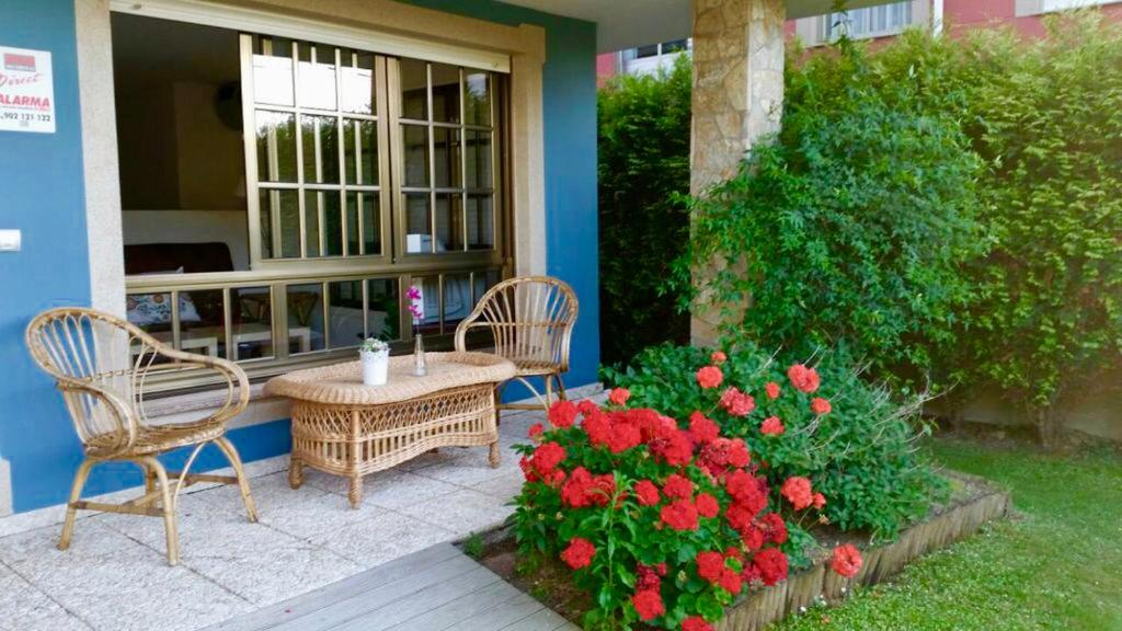 a patio with two chairs and a table and flowers at Housingcoruña Apartamento Playa Miño 01 in Miño