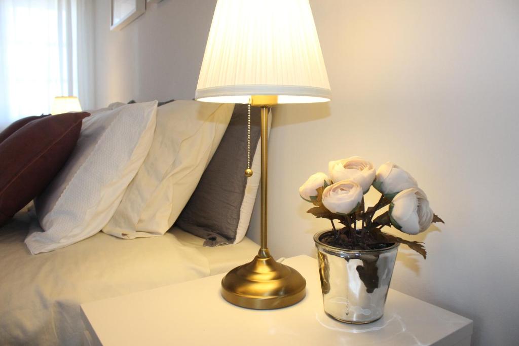 a lamp on a table with a vase of flowers at Vigia's Guest House in Viseu