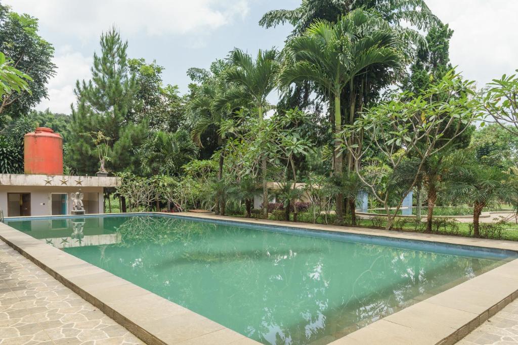 a swimming pool in a resort with trees in the background at RedDoorz Plus at Hotel Negeri Baru Lodaya Puncak in Bogor