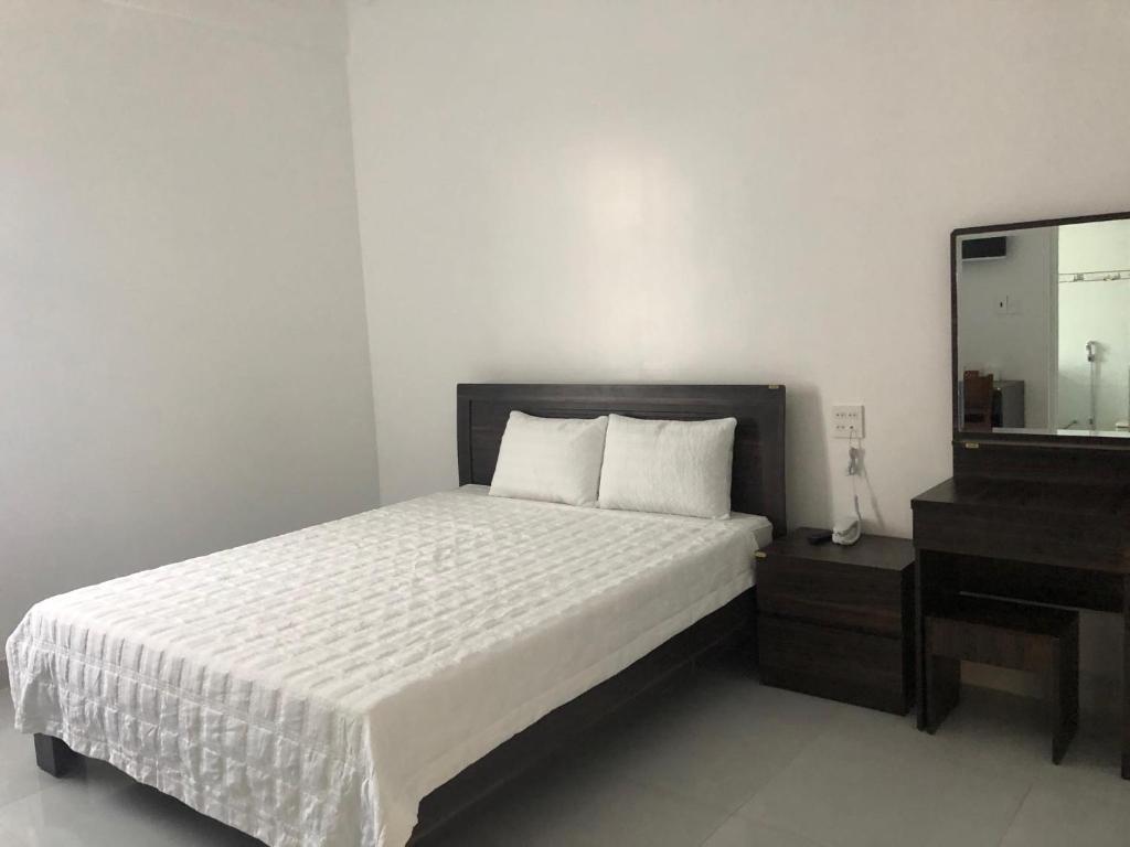 Schlafzimmer mit einem Bett, einer Kommode und einem Spiegel in der Unterkunft Ngoc Lan Hotel and Coffee in Ðưc Trọng