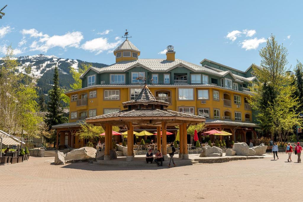 um grande edifício amarelo com um gazebo em frente em Bear Lodge (Town Plaza) em Whistler