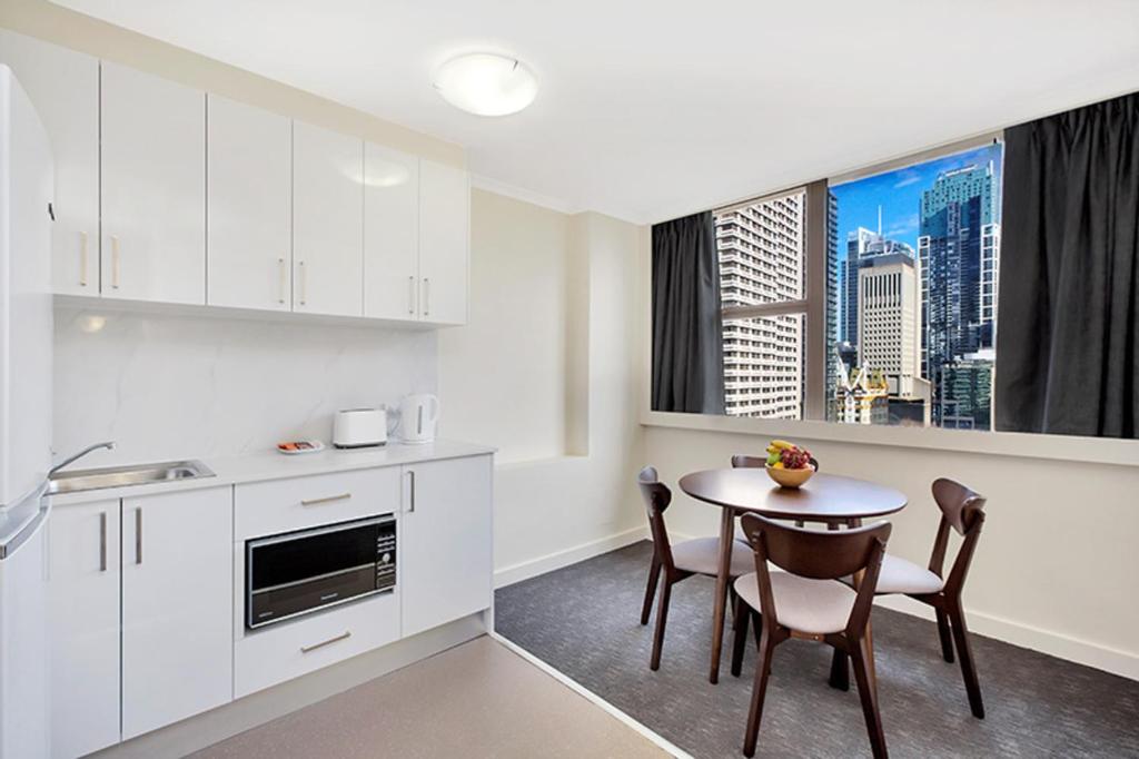 een keuken met witte kasten en een tafel met stoelen bij Park View Apartment in Sydney