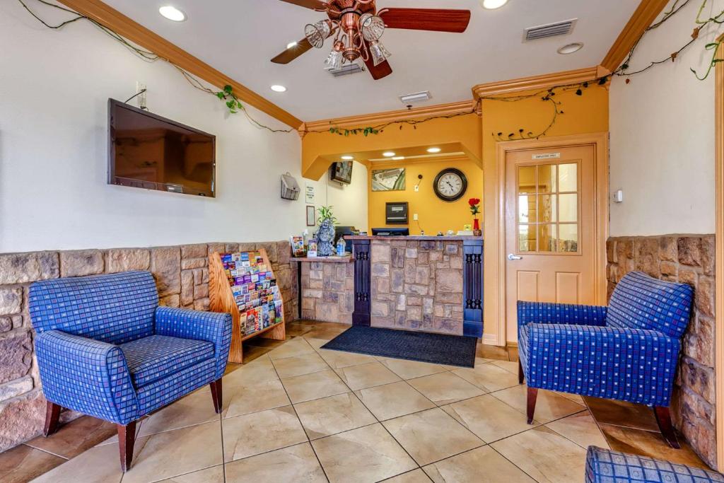 a living room with blue chairs and a bar at Quality Inn in Brownsville