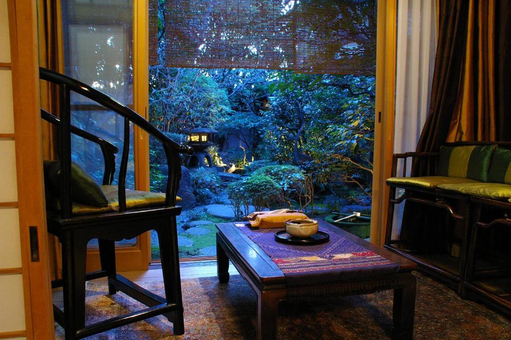 een kamer met een tafel, een stoel en een raam bij Seikoro Ryokan - Established in 1831 in Kyoto