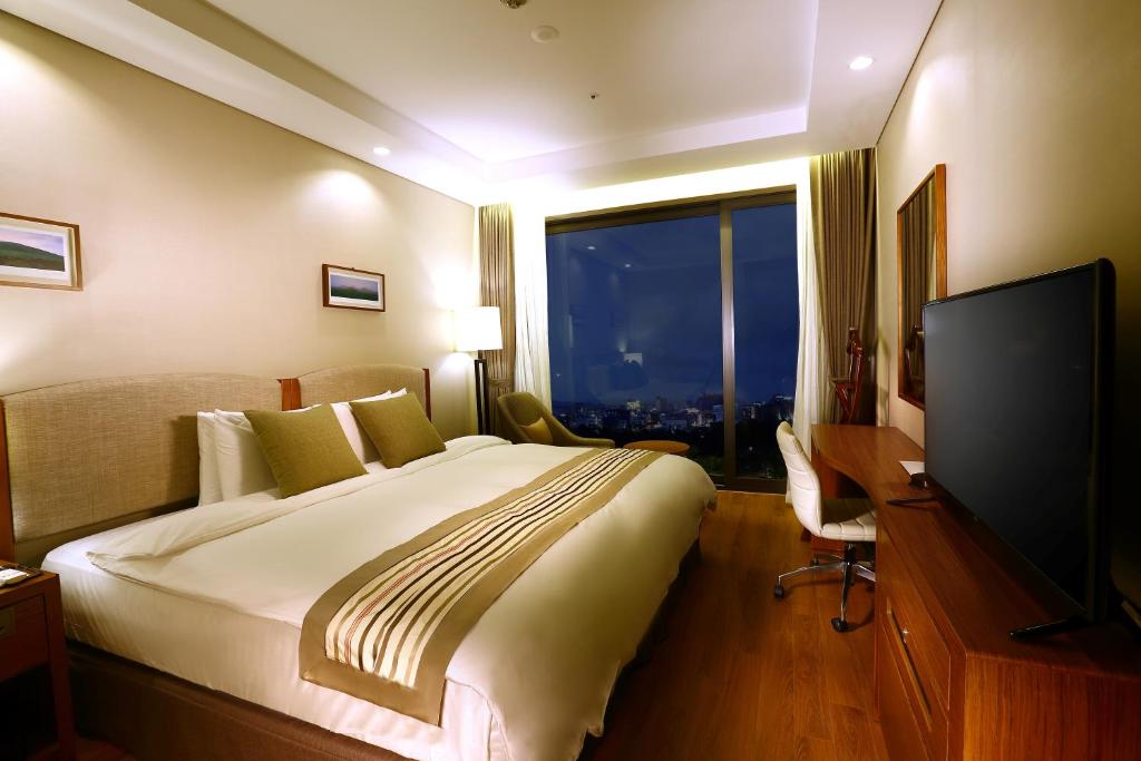 a hotel room with a large bed and a flat screen tv at Parksunshine Jeju in Seogwipo