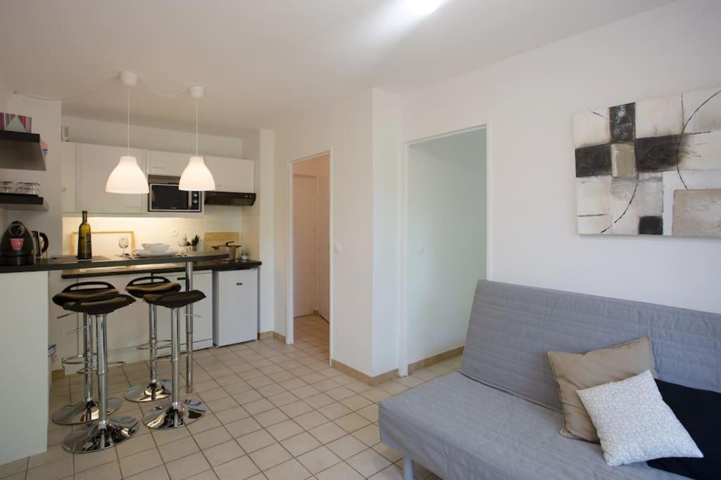 a living room with a couch and a kitchen at Dans un écrin de verdure in Hyères