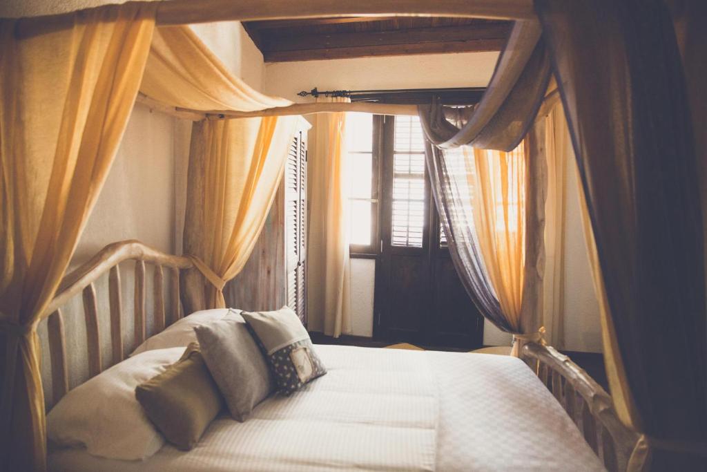 a bedroom with a bed with curtains and a window at The Iskemleci Guest House in North Nicosia