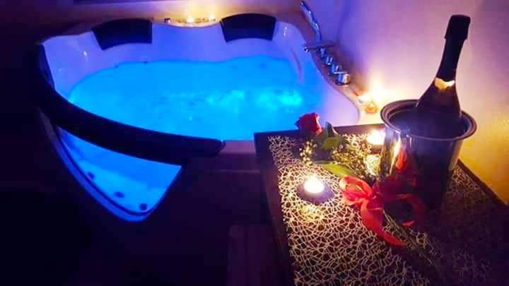 uma casa de banho com uma banheira, uma garrafa de vinho e uma vela em B&B Vistamareblu em San Foca